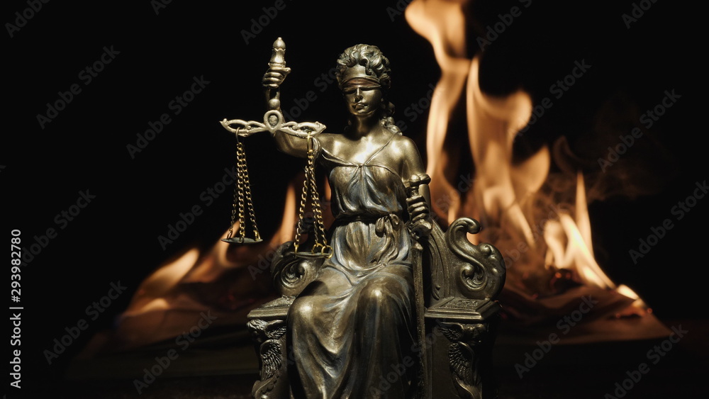 Statue of Lady Justice on the background of the flame of a burning book