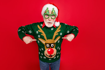 Photo of santa looking on unbelievable low x-mas shopping prices indicate fingers on cheap jumper wear x-mas tree shape specs ugly ornament sweater isolated red background