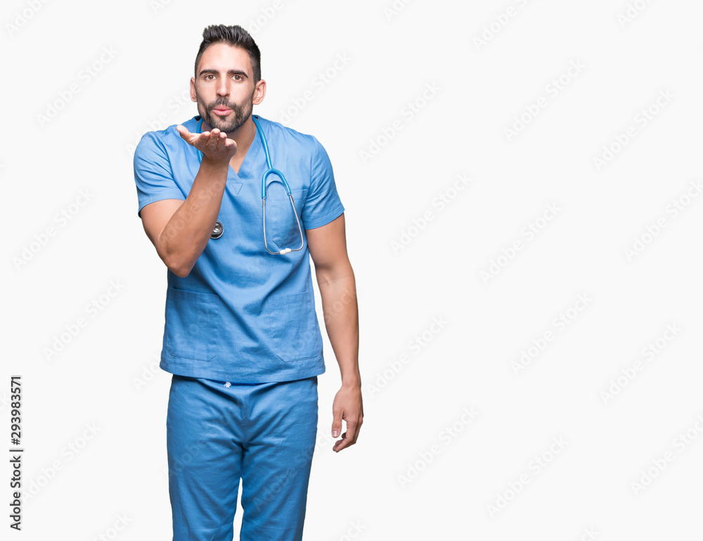 Handsome young doctor surgeon man over isolated background looking at the camera blowing a kiss with hand on air being lovely and sexy. Love expression. Handsome young doctor surgeon man over isolated background looking at the camera blowing a kiss with hand on air being lovely and sexy. Love expression.