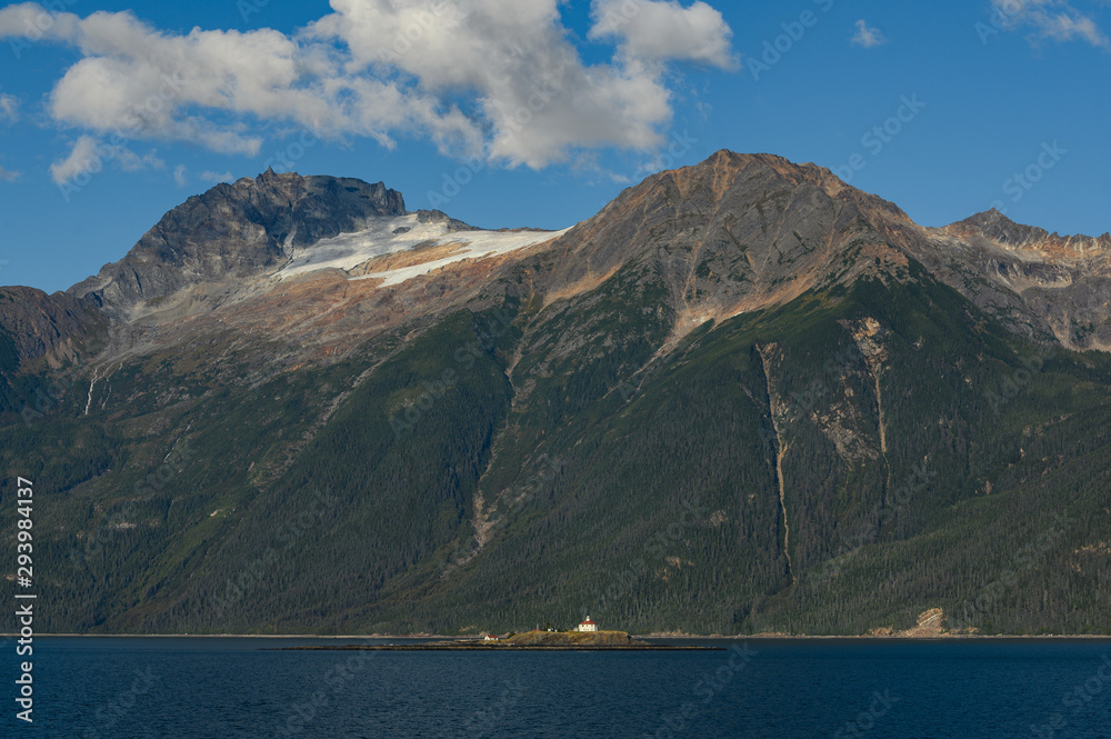 A small island in the ocean with houses on the background of mountains