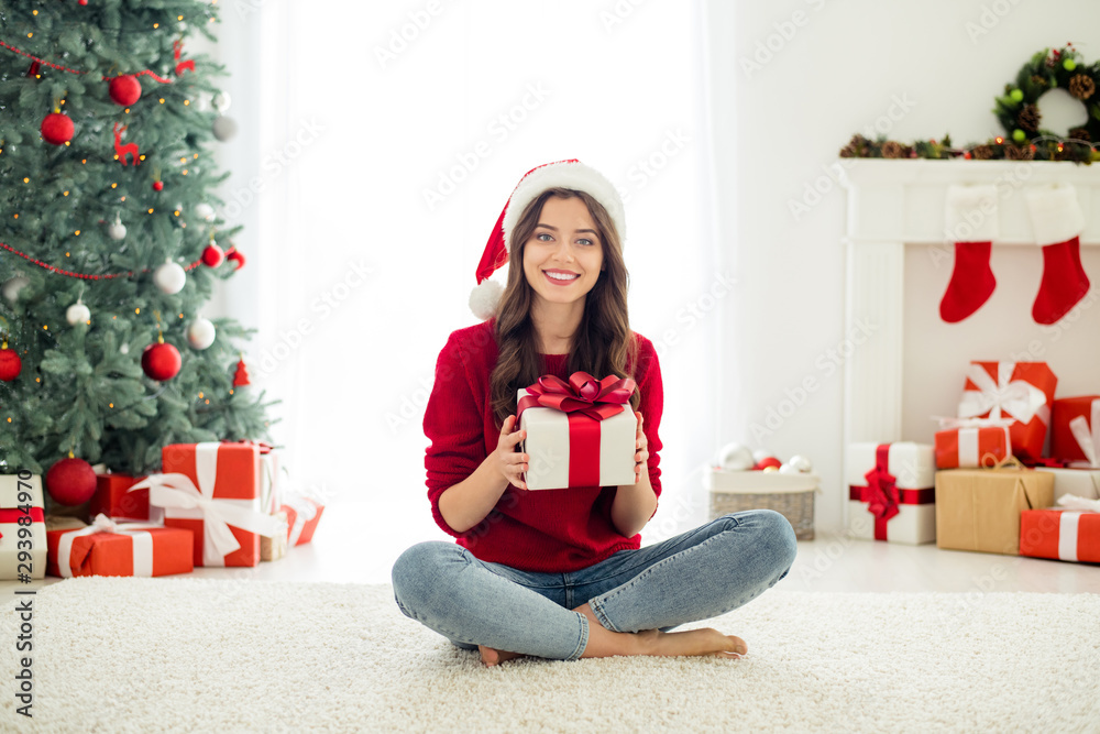 Full length body size photo of charming beautiful attractive pretty sweet girlfriend showing you her wrapped present sitting with crossed legs on floor carpet wearing jeans denim Full length body size photo of charming beautiful attractive pretty sweet girlfriend showing you her wrapped present sitting with crossed legs on floor carpet wearing jeans denim