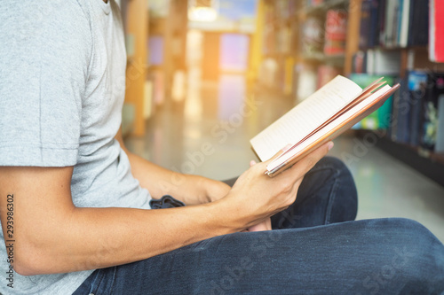 Side view of male student reading books in library.