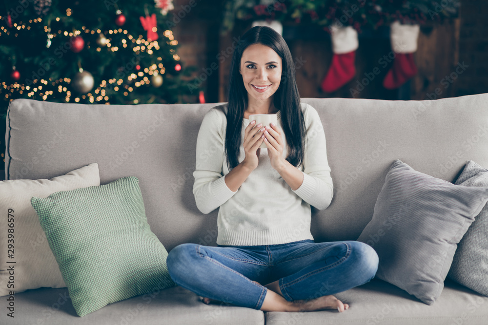 Full length photo of positive cheerful girl in white pullover sit on divan have holly christmas holidays hold mug with hot beverage eggnog enjoy newyear celebration in house with noel ornament Full length photo of positive cheerful girl in white pullover sit on divan have holly christmas holidays hold mug with hot beverage eggnog enjoy newyear celebration in house with noel ornament