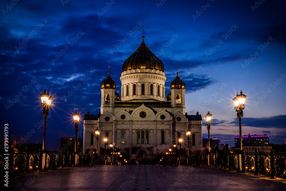 Illuminated Cathedral of Christ the Savior framed with old style street lights of Patriarchy Bridge at night.