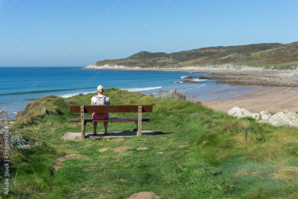Lady gazing at the ocean off the North Devon coast of England on the coast path near Woolacombe in Devon