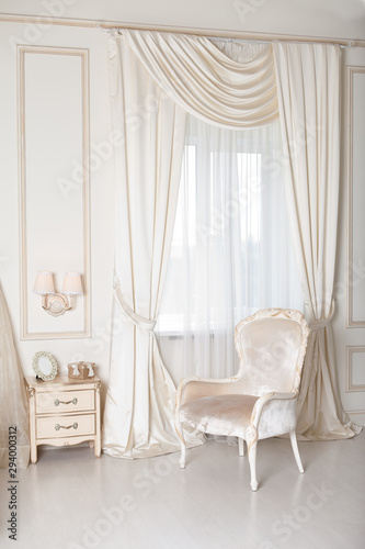 Elegant arm-chair with near a window. Luxury interior in white colors. Armchair with velvet upholstery