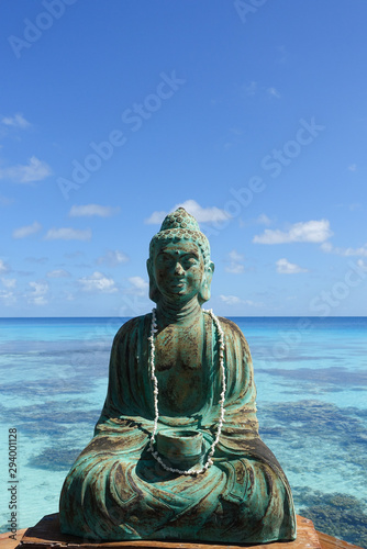 A figure of Buddha in front of a turquoise lagoon on the island of Fakarava in French Polynesia in the South Pacific  copy space