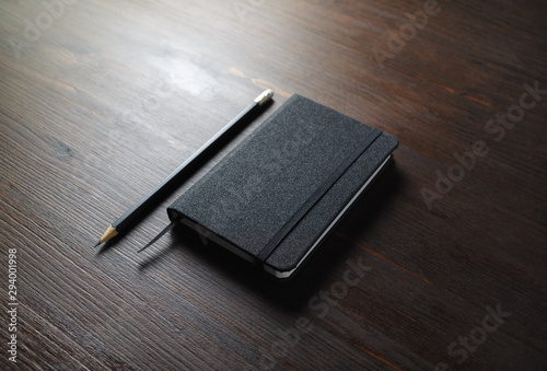 фотографія Black notebook and pencil on wooden background