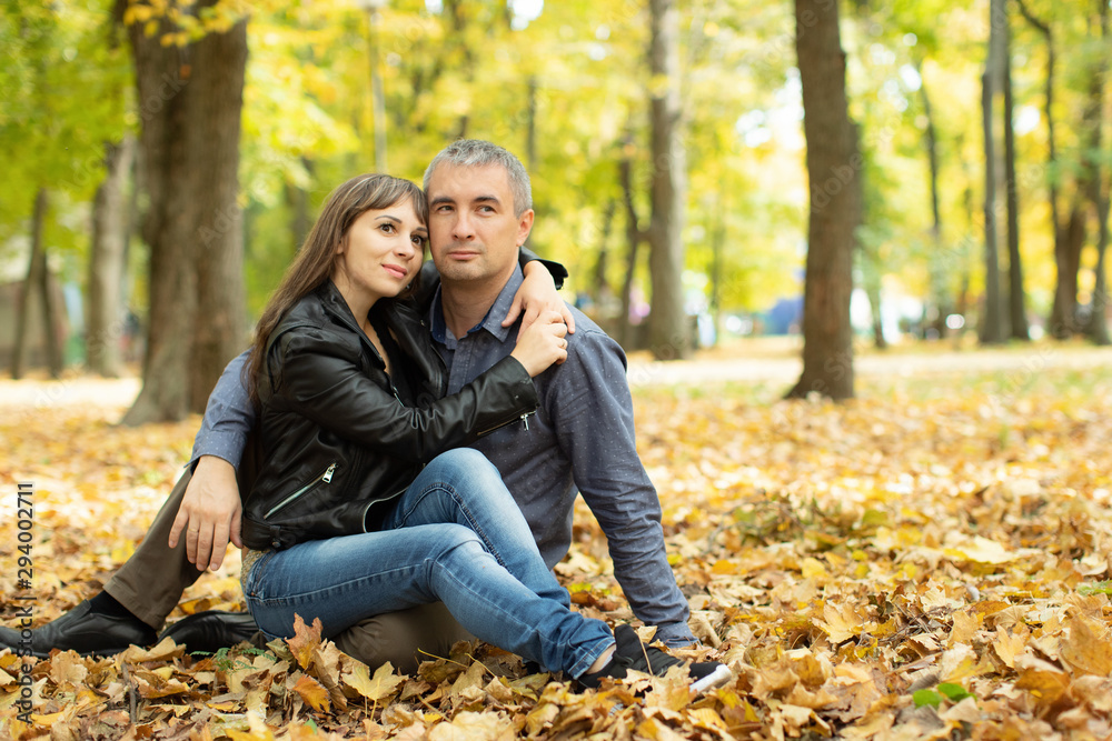 Love couple sitting on yellow leaves in autumn park. Happy man and woman hugging, enjoying good weather, romantic date, autumn leisure. Love couple sitting on yellow leaves in autumn park. Happy man and woman hugging, enjoying good weather, romantic date, autumn leisure.