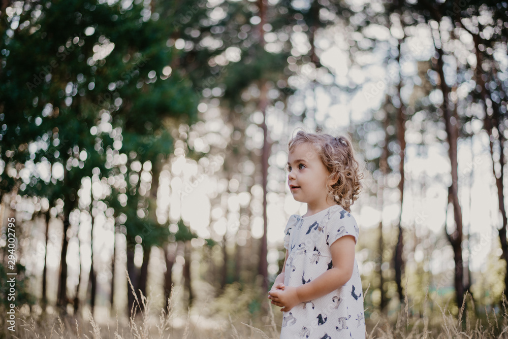 Naklejka premium cute little girl in the sunny forest