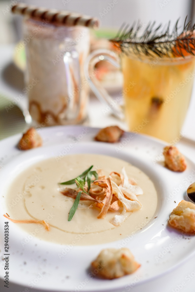 Conceptual cream soup in a white plate on a white table in a restaurant, cool plan. space