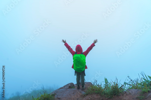 Backpacker Hiking On Mountain Peak Cliff after heavy rain with fog background