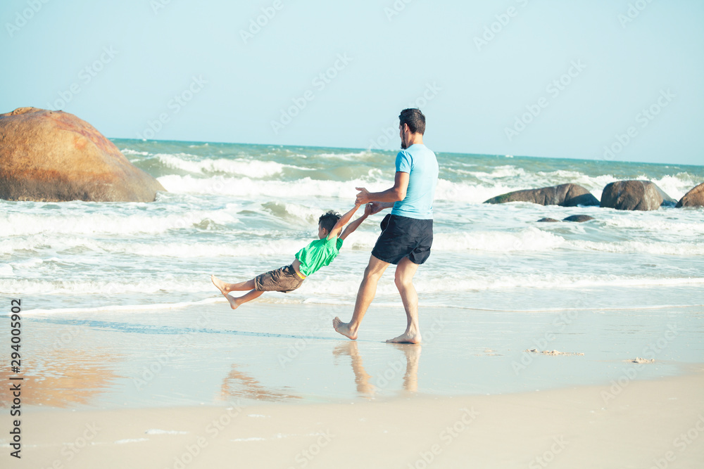 happy family on beach playing, father with son walking sea coast, rocks behind smiling taking vacation happy family on beach playing, father with son walking sea coast, rocks behind smiling taking vacation