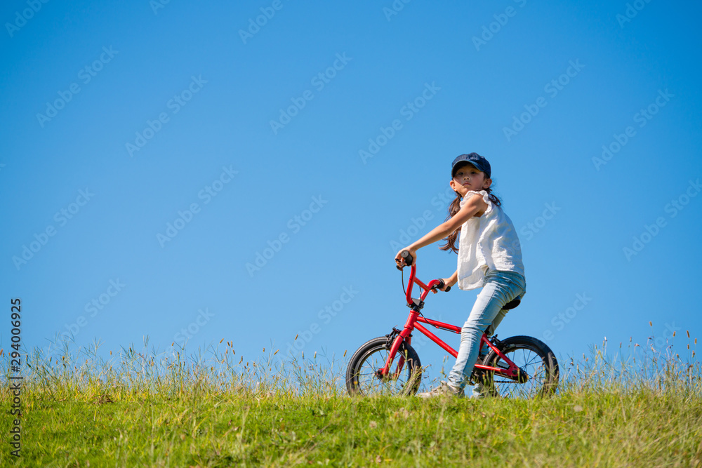 Fototapeta premium 草原で自転車に乗る女の子