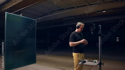 Shooting gallery. A young man preparing the gun and shooting with a firearms. A smoking gun. A concentrated young man shooting on a shooting range. Spark. Bullet. Shot.