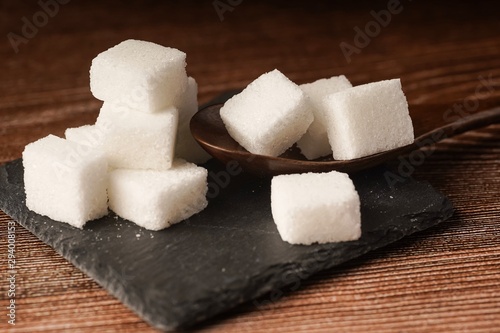 Sugar cubes with wooden spoon. Unhealthy eating concept