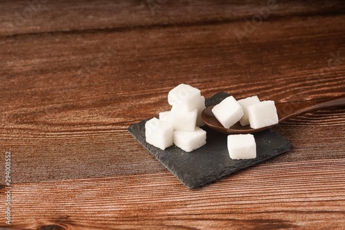 Sugar cubes with wooden spoon. Unhealthy eating concept