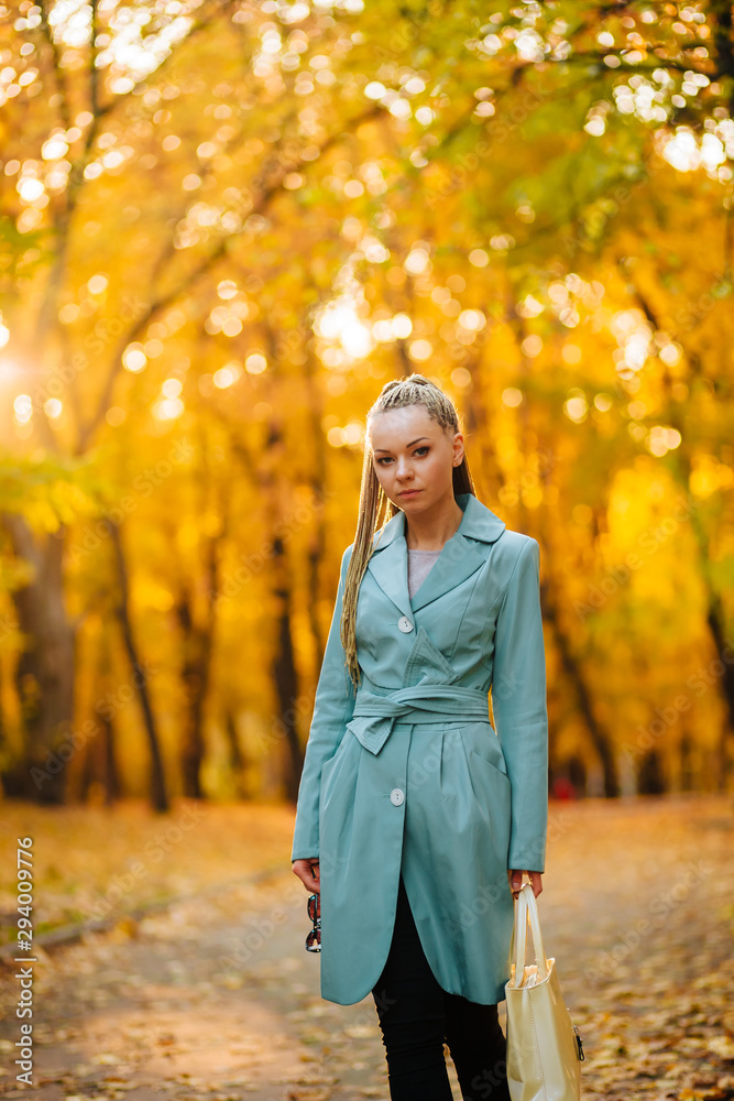 Girl walking in the Park in the autumn with a white bag in a coat Girl walking in the Park in the autumn with a white bag in a coat
