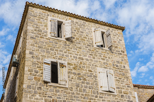 building is made of stone with a tiled roof and wooden shutters on the windows