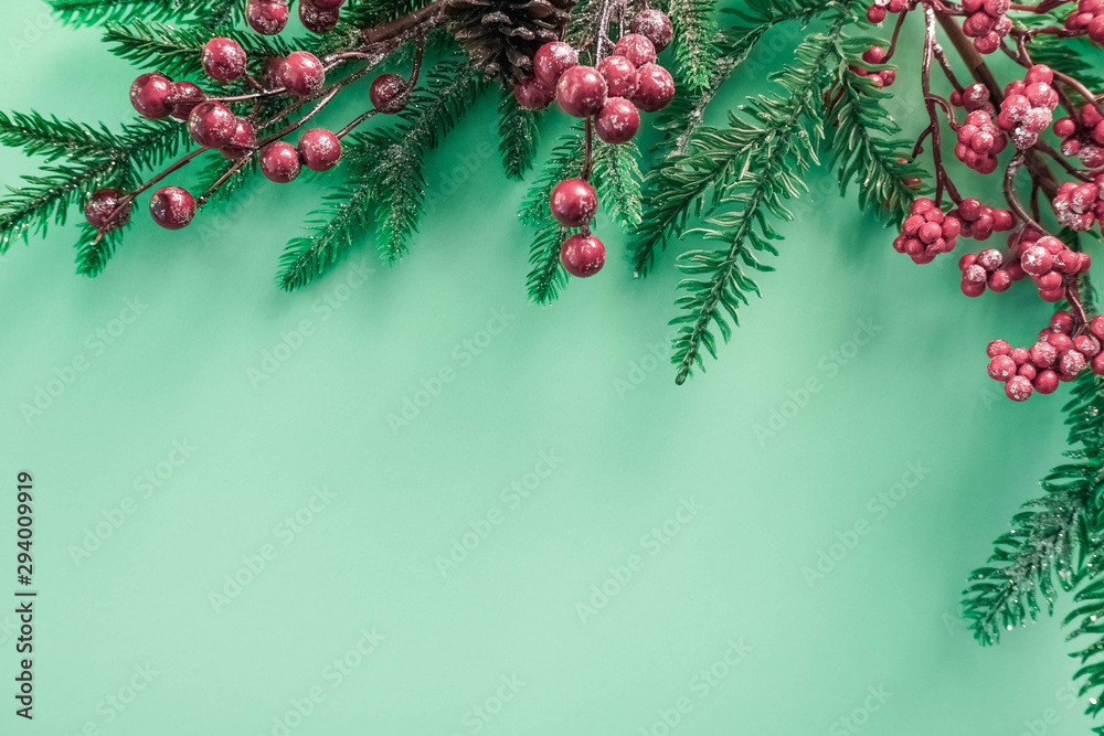 Christmas decorations with red berries and fir branches on a beautiful mint background