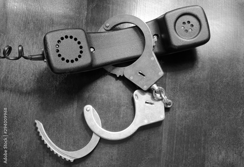 Obraz premium Telephone reciever with handcuffs close up