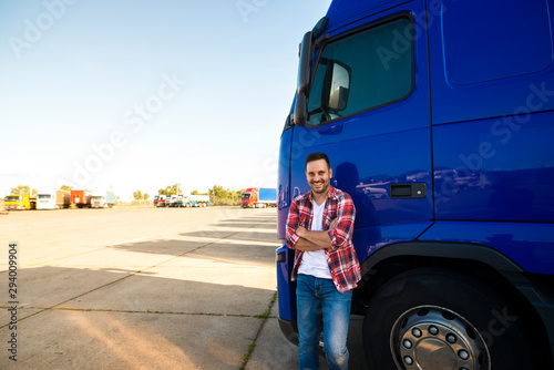 Portrait of smiling trucker standing by his truck ready for driving. Driver occupation. Transportation services.