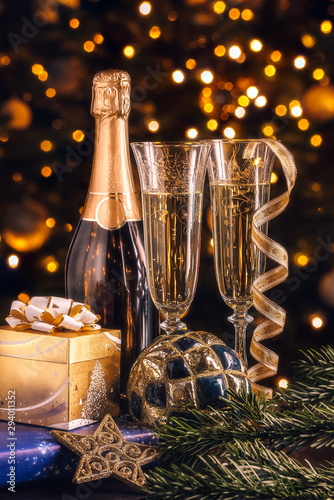 New Year composition. Bottle of champagne with decoration in front of Christmas tree