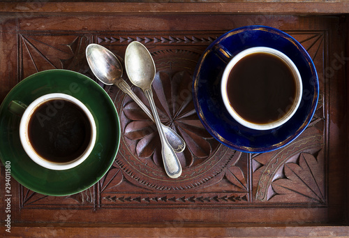 Two vintage cups of espresso and spoons on the vintage wooden salver top view