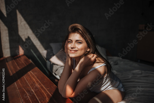 Girl sitting on the bed by the window in the sunlight © Smeilov