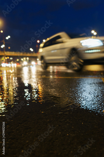 Modern city, cars on the road and bad weather. Reflection of pedestrians and cars in the water.