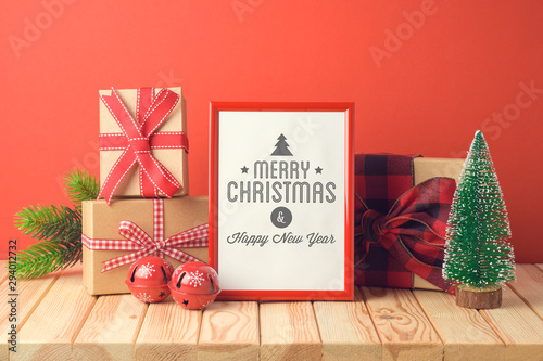Christmas holiday celebration concept with photo frame, gift boxes and pine tree on wooden table.
