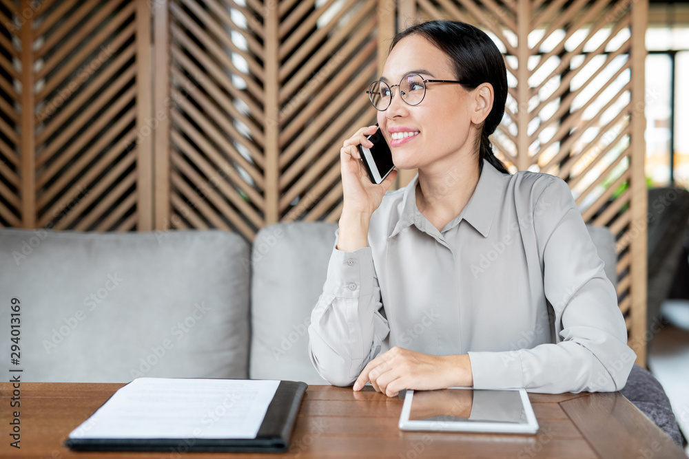 Busy young employee in smart casualwear consulting client on mobile phone Busy young employee in smart casualwear consulting client on mobile phone