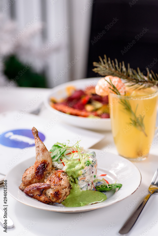 Tobacco chicken with salad on a white table in a restaurant. Tea and dessert on a blurred background. Large plna. Space Tobacco chicken with salad on a white table in a restaurant. Tea and dessert on a blurred background. Large plna. Space