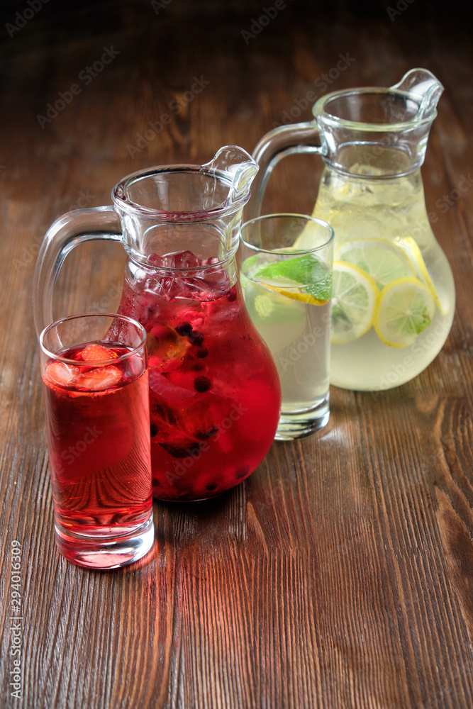 Different soft drinks in transparent jugs on a dark wooden background. menu for catering