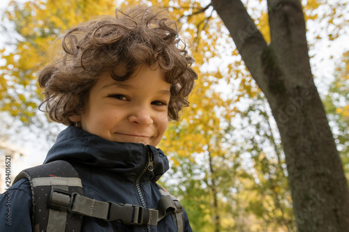 Joy of autumn. Portrait of cute curly 6 year old boy on the background of autumn foliage.