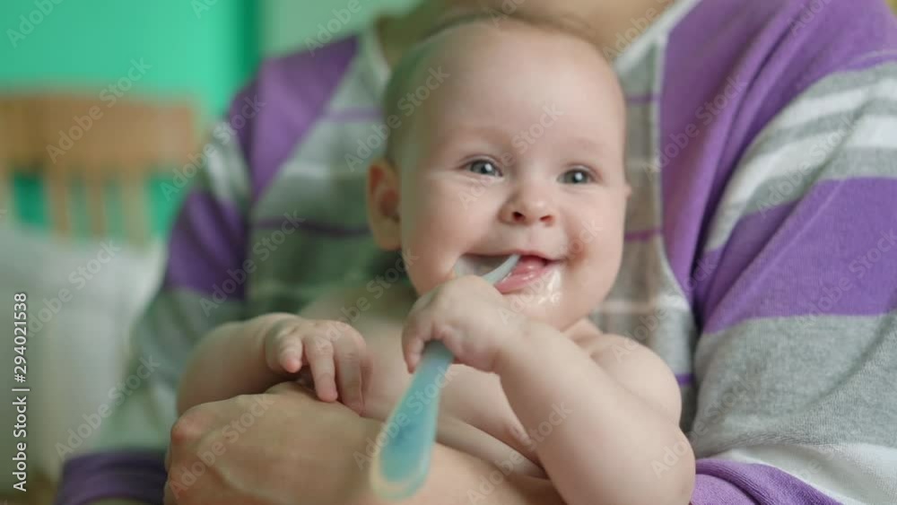 Adorable baby with spoon in mouth looking at camera Adorable baby with spoon in mouth looking at camera