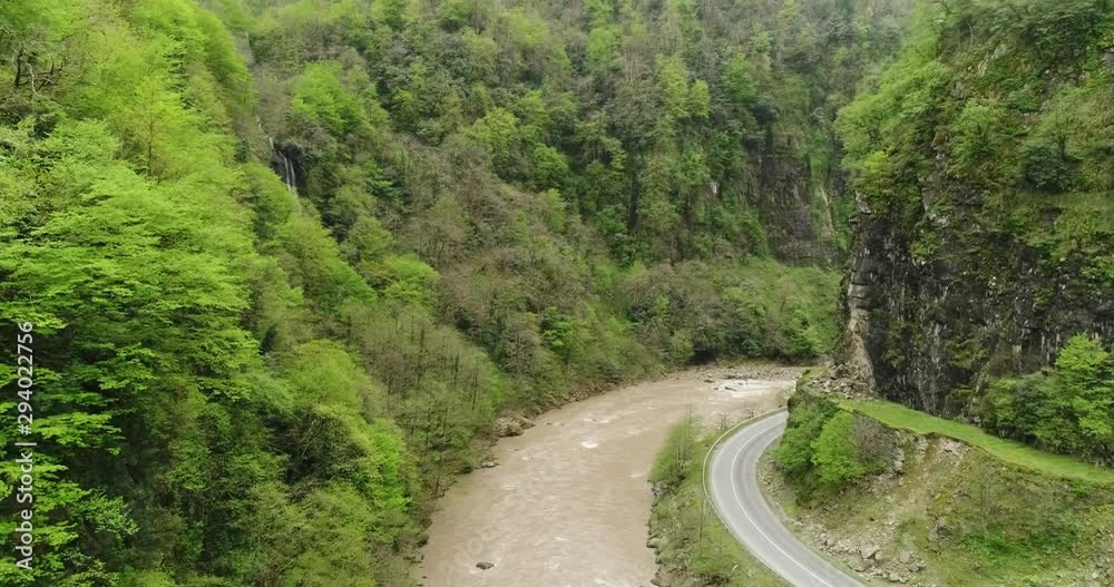 River flowing between mountainous forest and road curve. 4K aerial footage River flowing between mountainous forest and road curve. 4K aerial footage