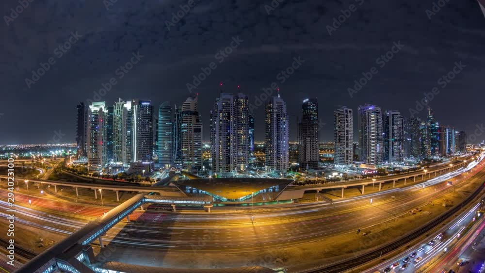 Aerial panoramic view to Sheikh Zayed road from Dubai Marina with JLT illuminated skyscrapers night timelapse, Dubai. Traffic, bridges and metro line with tram stop. United Arab Emirates Aerial panoramic view to Sheikh Zayed road from Dubai Marina with JLT illuminated skyscrapers night timelapse, Dubai. Traffic, bridges and metro line with tram stop. United Arab Emirates