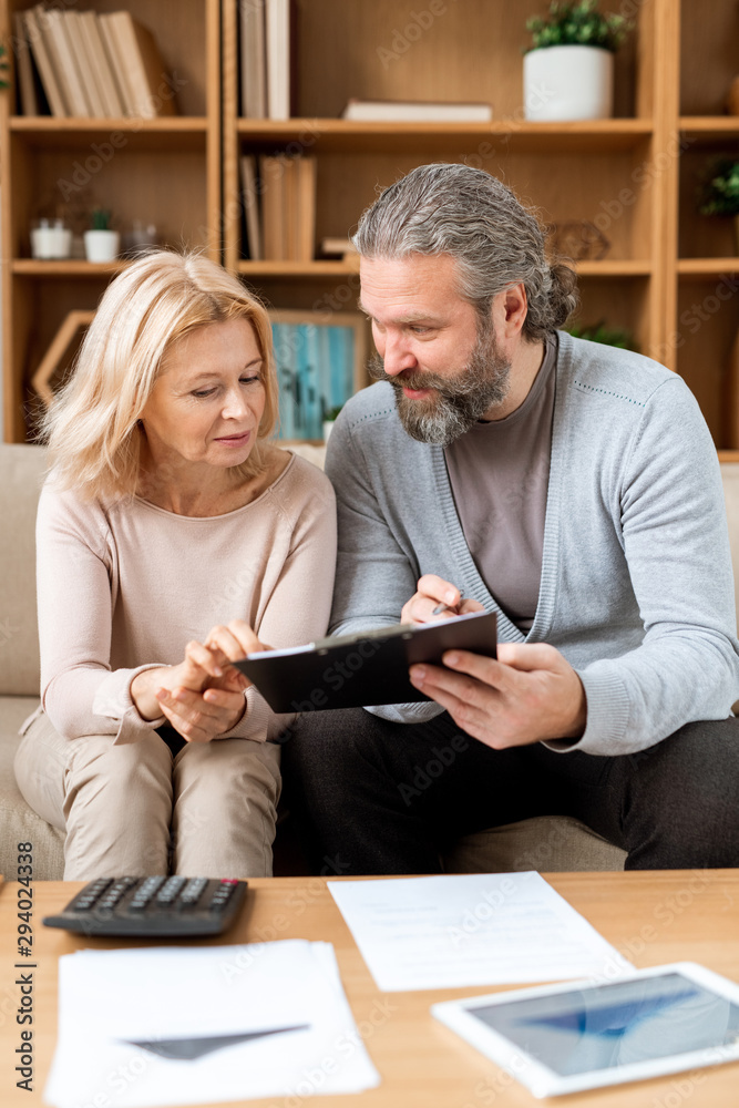 Mature man and woman reading terms of contract while going to buy new house Mature man and woman reading terms of contract while going to buy new house