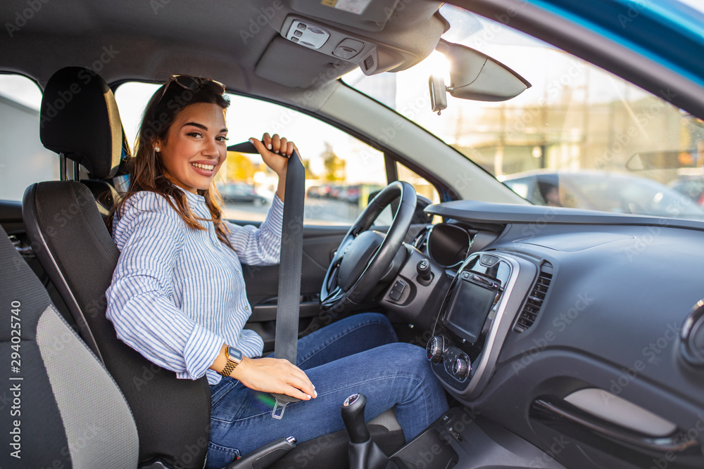 Safety first. Beautiful caucasian lady fastening car seat belt. Pretty young woman driving her new car. Pretty young woman driving her new car. Female fastening safety belt in car
