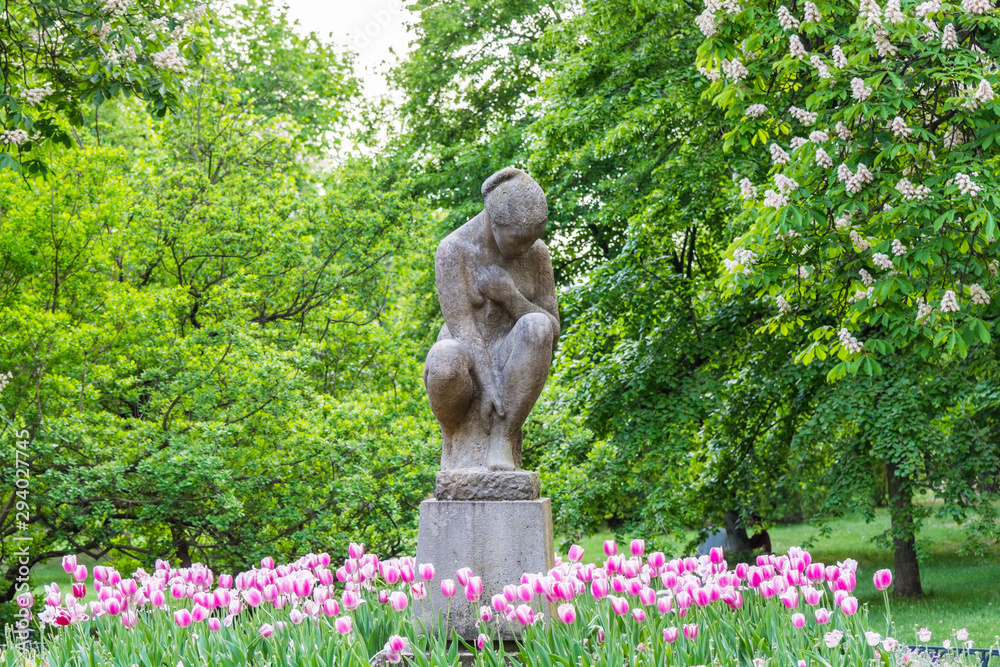 Φωτογραφία A woman statue in the Letna park, with background of tulips flowers,  in Prague, Czech Republic