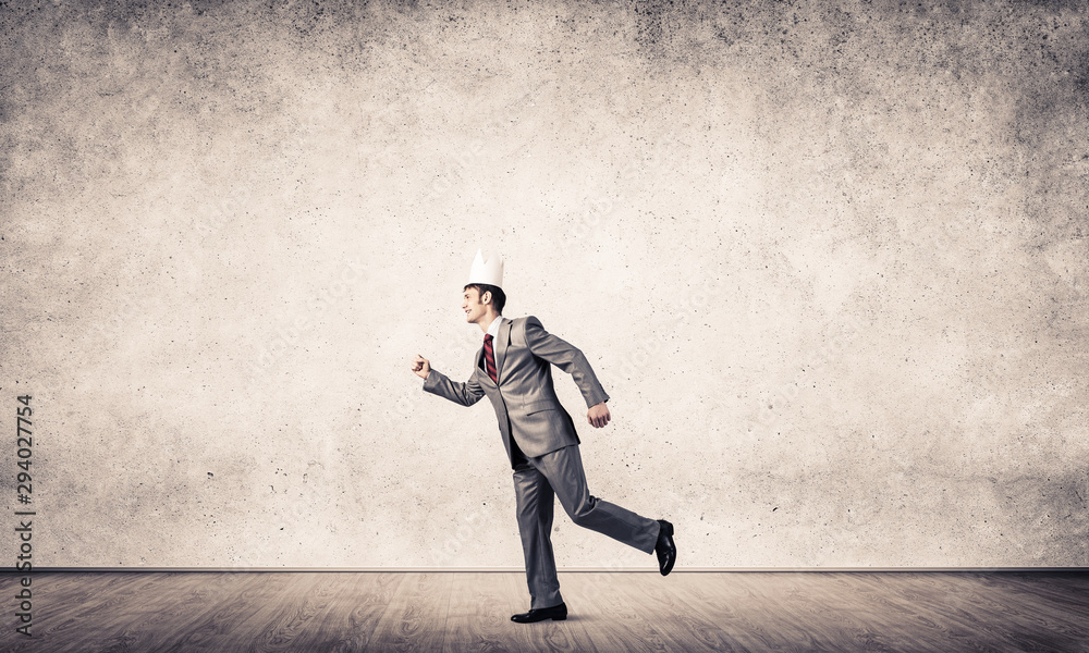 King businessman in elegant suit running in empty room with wooden floor