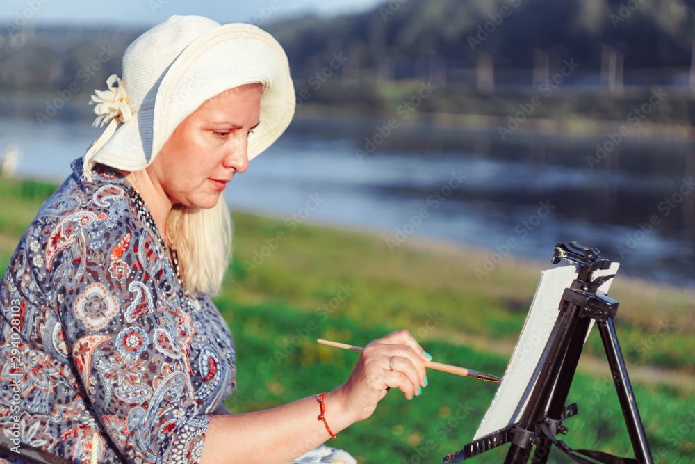 Obraz premium an elderly woman paints a picture in nature