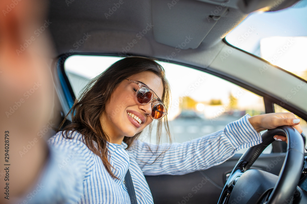 Road trip selfie. Young woman using her smartphone and making selfie while driving a car. Young woman taking selfie picture with smart phone camera in car. Smiling young woman taking selfie picture Road trip selfie. Young woman using her smartphone and making selfie while driving a car. Young woman taking selfie picture with smart phone camera in car. Smiling young woman taking selfie picture