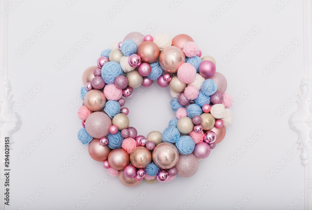 wreath of Christmas balls and clews on white wall. New year decoration in tender pink and blue colors wreath of Christmas balls and clews on white wall. New year decoration in tender pink and blue colors