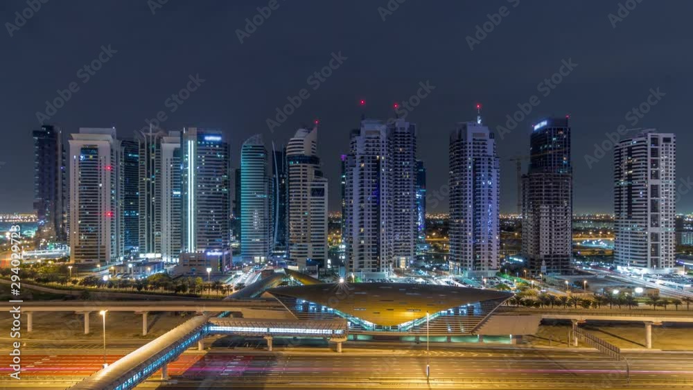 Aerial panoramic view to Sheikh Zayed road from Dubai Marina with JLT illuminated skyscrapers during all night timelapse with lights swithcing off, Dubai. Traffic, bridges and metro station. United Aerial panoramic view to Sheikh Zayed road from Dubai Marina with JLT illuminated skyscrapers during all night timelapse with lights swithcing off, Dubai. Traffic, bridges and metro station. United
