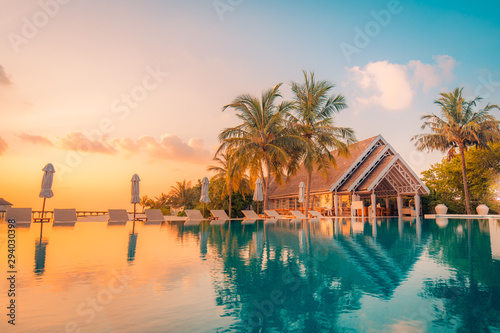 Luxury summer travel and vacation. Beautiful poolside and sunset sky landscape. Luxurious tropical beach landscape, deck chairs and loungers and water reflection. © icemanphotos