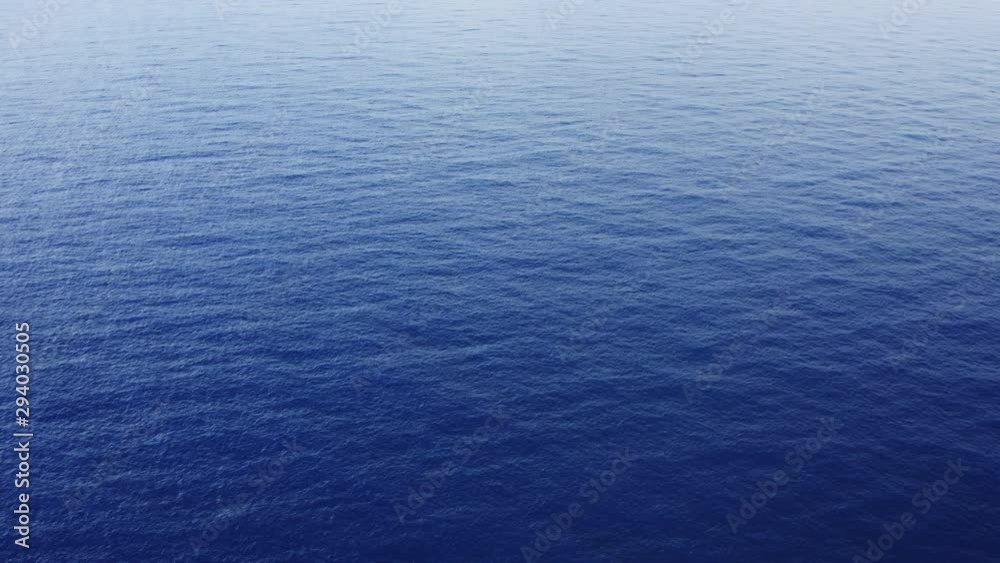 Aerial shot flying over endless tropical blue ocean background 