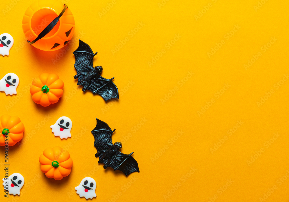 Halloween holiday concept, Spooky pumpkin bucket, black spider, bats and tiny ghost in orange background with copy space for text, Top flat view wallpaper