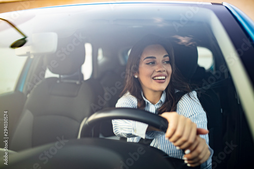 Canvas Print Beautiful young happy smiling woman driving her new car at sunset